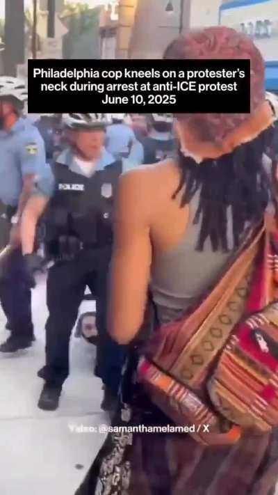 Cop kneeling on a woman's neck while other cops use bikes to shield him from cameras.