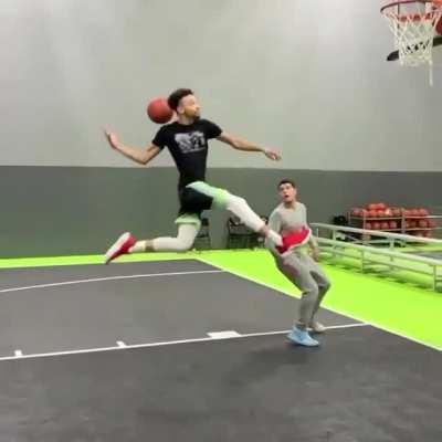 The basketball slides behind him before being dunked