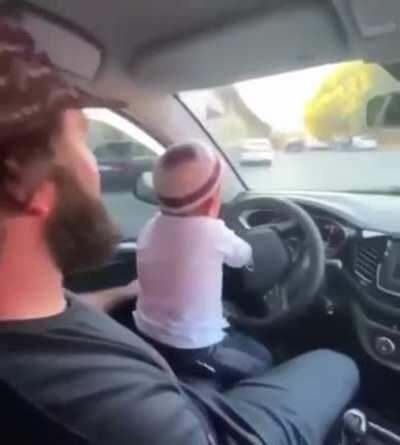 Lil person driving a car in the city