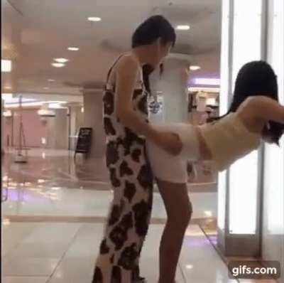 Asian girls playful humping in a mall