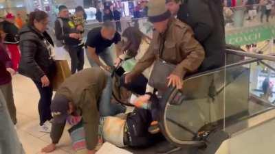 Guy pretends to drop his keys on an escalator, which causes people to fall over each other