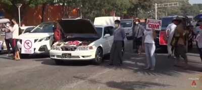 Protestors in Myanmar pretend their cars are broken down to block the Military.
