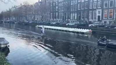 Sinterklaas on his electric surfboard on the canals of Amsterdam