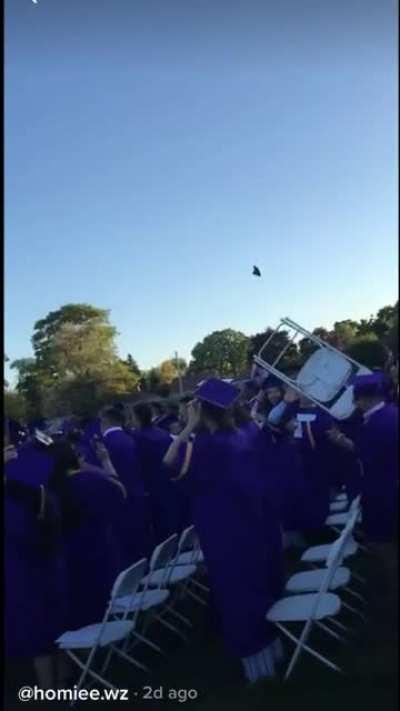 Someone throws a chair instead of a cap at a graduation ceremony