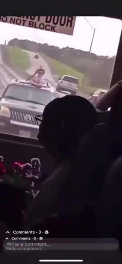 Idiot hanging out of sunroof pulls a gun on a school bus. Local authorities are investigating and searching for the suspect(s).