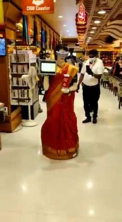 An automated mannequin draped in Saree walking around giving sanitisers to customers at a popular textile chain in Tamil Nadu