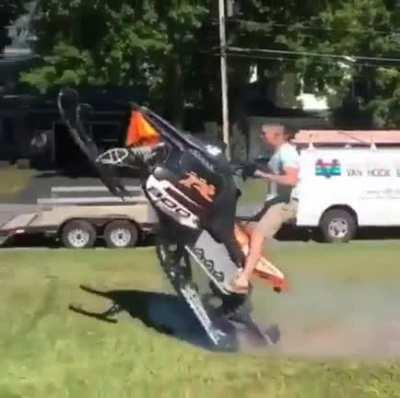 Dude trying to ride the snowmobile in the front yard