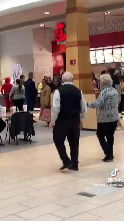 Older couple happily dancing in mall food court