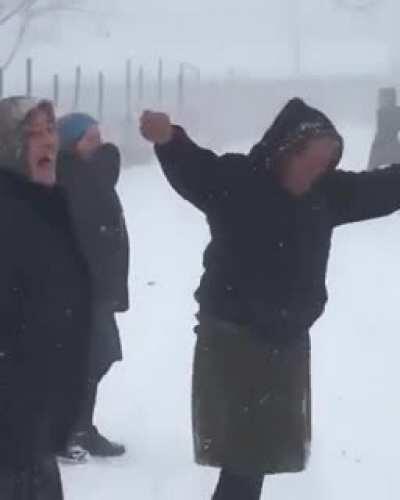 Babushka throws snow at friend.