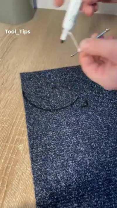 Cutting carpet to fit around a pipe.