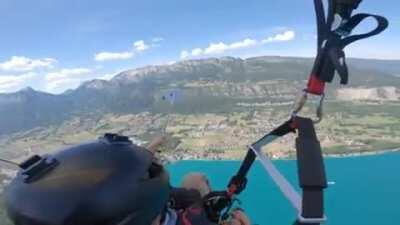 Girl paragliding with an instructor in the Alps, drops her Iphone whilst holding it on a selfie stick