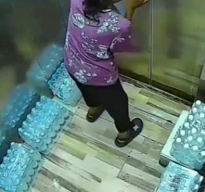 Woman slips herself through the slit of a stopped elevator