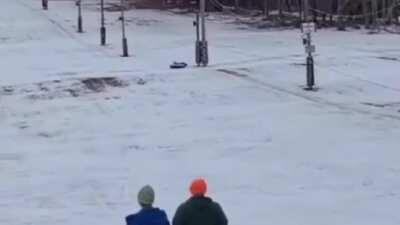 Person riding a snow tube loses his boots after smashing into a pole