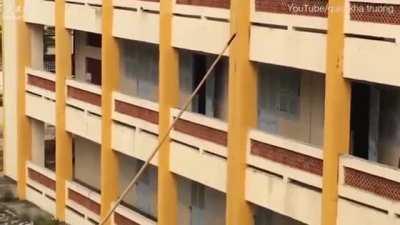 Vietnamese tactical team using bamboo pole to climb up a wall.