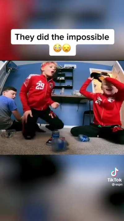 Two kids flip bottles simultaneously landing successfully on top of each other