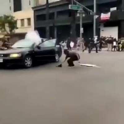 Rioter gets a firework thrown back in his car.