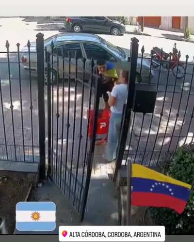 En Cordoba, un repartidor de PedidosYa con una bandera de Venezuela a cuestas deja una entrega y quien recibe el pedido lo abraza para festejar la caida del dictador Maduro