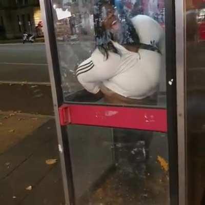 British lady takes a dump in a phone booth.