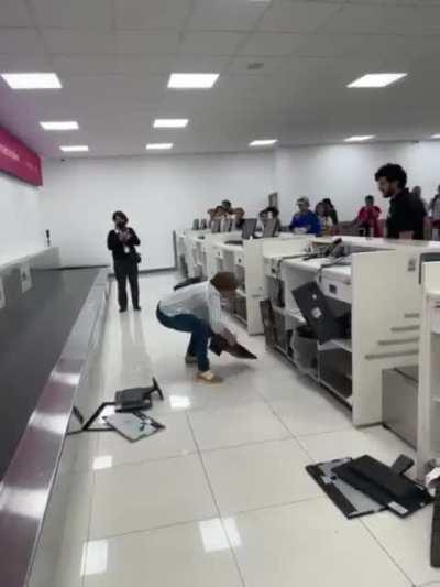 Woman destroys computers at airline's counter as a complaint of a cancelled flight she says "Don't give me my money back, I don't give a damn, But this is gonna cost you"