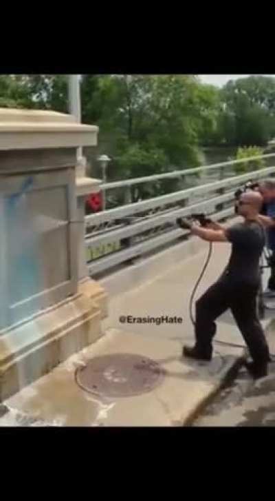 Skinhead draws fascist symbol on a wall