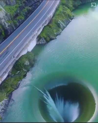 The morning-glory-type spillway of the Monticello Dam looks like a watery black hole.