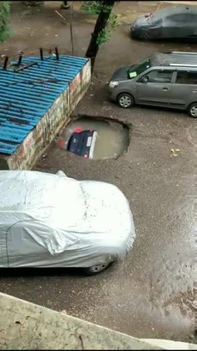 Car gets devoured by a large pothole