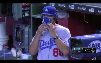Dodgers bench coach Bob Geren pulls down his mask to cough into the open air during in-game interview
