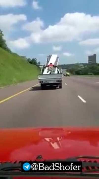 Using your body to secure materials on the back of a moving pick-up truck...yeah good idea.