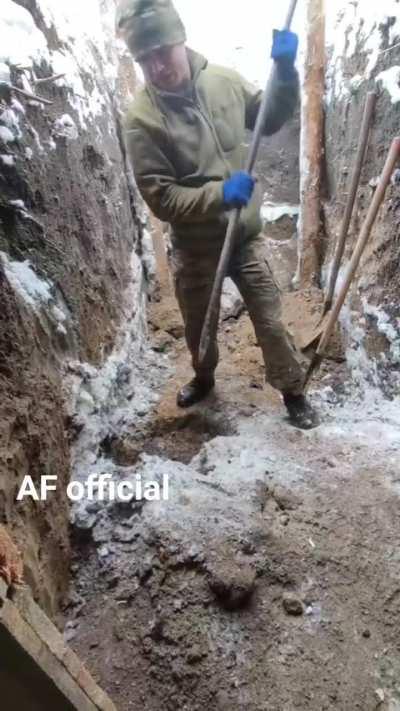 Ukrainian soldier puts some effort into improving his position in frozen ground.
