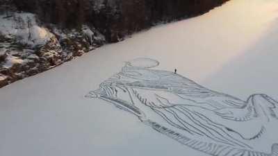 Man draws a huge fox on a snow-covered frozen lake in Finland using a shovel