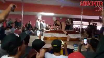 A stripper dances on a dead man's coffin at funeral