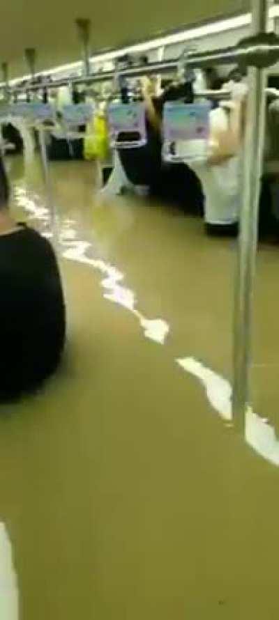 Subway passengers trapped waist-high in floodwaters as Chinese river banks burst