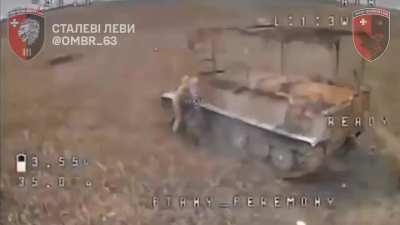 Two Russian soldiers by an abandoned MT-LB are attacked by two Ukrainian FPV drones at the same time