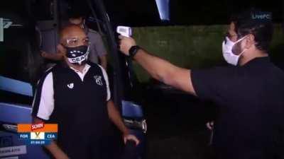 Organizers taking the temperatures of the people getting off the bus at a Brazilian football clubs meeting.