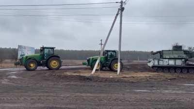 Ukrainian farmers towing an abandoned Russian Tor-M2 short-range air defense system