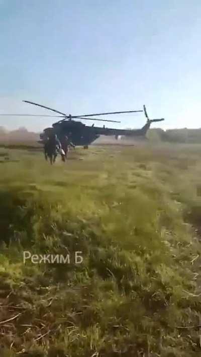 RU pov: Russian troops evacuate wounded to an Mi-8 while a KA-52 helicopter keeps overwatch