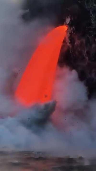 Molten lava rushing into the ocean like a waterfall