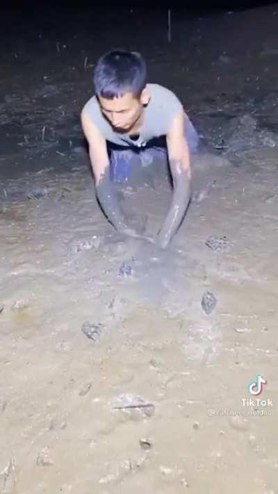 A guy catches an eel in the mud?