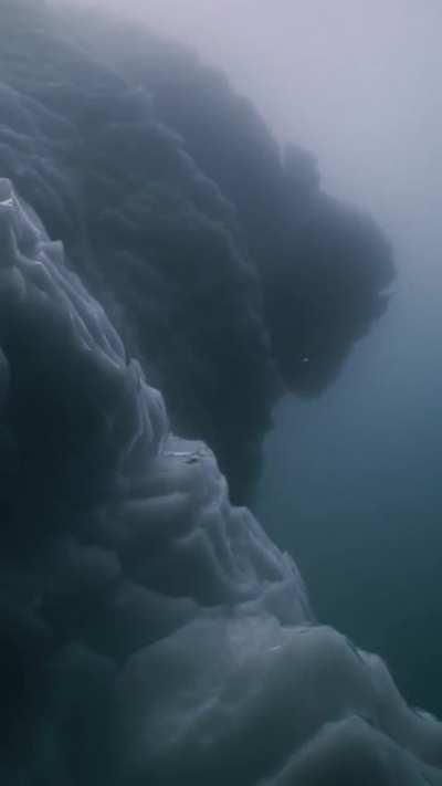 Shadows beneath an iceberg on a cloudy day near Greenland