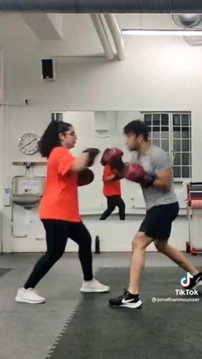 Guy teaches his sister to be his boxing trainer. She excels at the task.