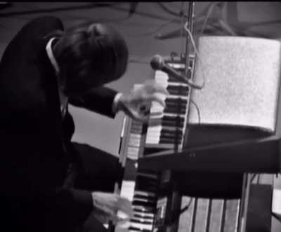 Ray Manzarek of the Doors performing a mesmerizing organ solo with his left hand on a keyboard bass, and his right hand on a Gibson organ. 1968.