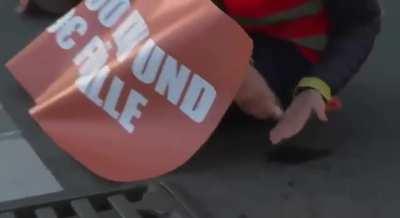 eco-activist glued himself to the asphalt and throws the glue tube into the rain drain