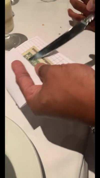 Waiter puts a butter knife completely through the dollar without cutting the dollar. (It was my dollar and when he gave it back it had no rips, tears, or cuts in it)