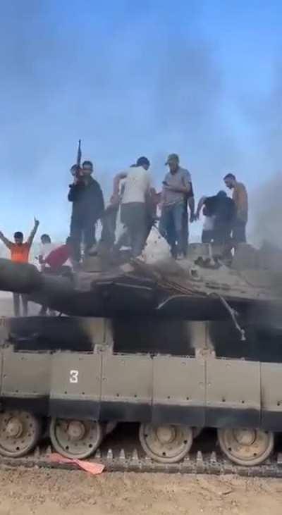 Palestinian terrorists pull an Israeli tank driver out of his Merkava tank after smashing through the Israeli border fence with Gaza with the use of bulldozers