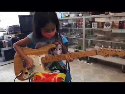 Little girl trying out a guitar in a shop