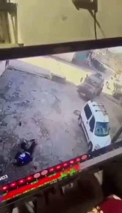 CCTV. A point blank execution of a wounded Palestinian. Israeli, IOF open fire on a group of young Palestinians, as the military vehicles approach, everyone runs away. Soldiers shoot and hit one the young men. The military vehicle then stops just next to 