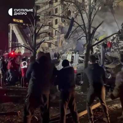 People are assisting emergency services near the destroyed apartment building in Dnipro by clearing debris, protecting the territory, and helping residents. Source: Suspilne Dnipro