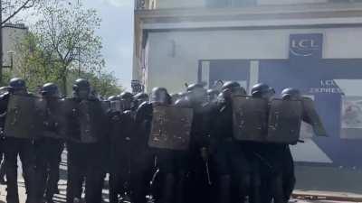 May-Day in France, a riot cop misses a grenade throw, gets stuck in the upper body part of one of his colleague, in a dense pack of cops.