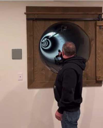 What is this tunnel in the wall of some building that this man is shooting down?