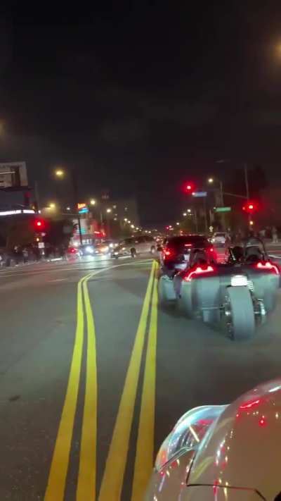 Street level view of van doing donuts that narrowly hits pedestrians and protesters in Los Angeles